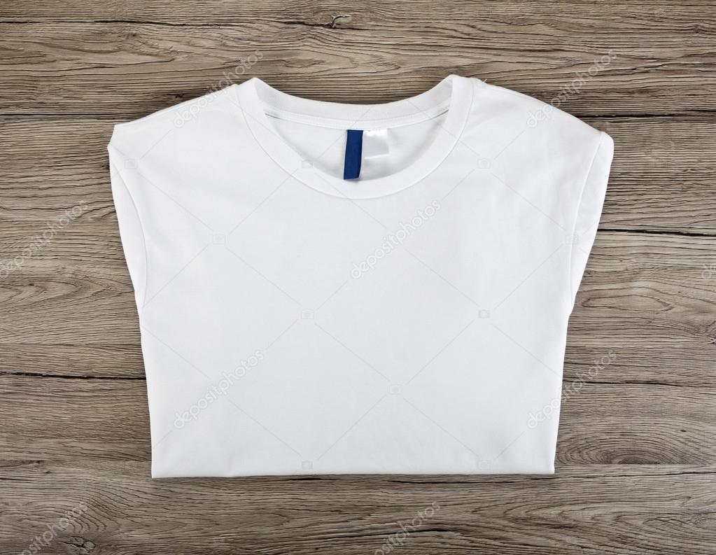White folded t-shirt template on a wooden background.