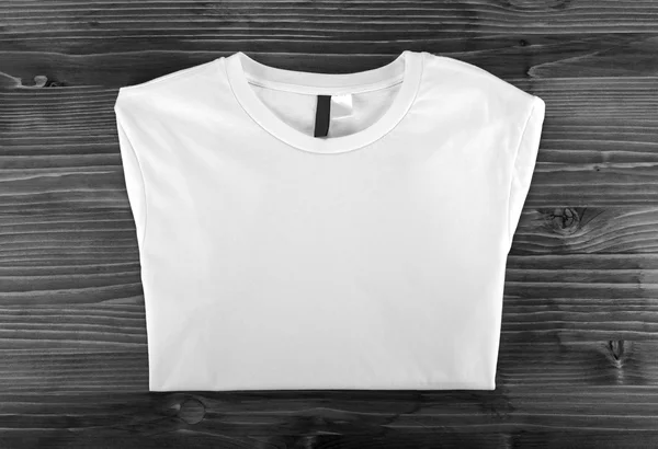 Weiße gefaltete T-Shirt-Vorlage auf einem hölzernen Hintergrund. — Stockfoto