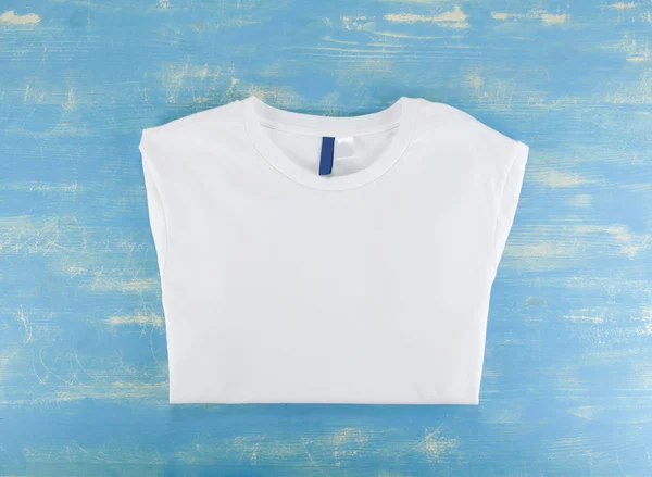 Weiße T-Shirt-Vorlage auf blauem Holzhintergrund. — Stockfoto