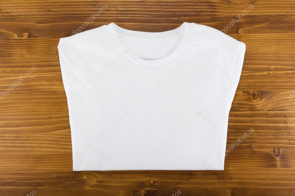 White folded t-shirt template on a wooden background.