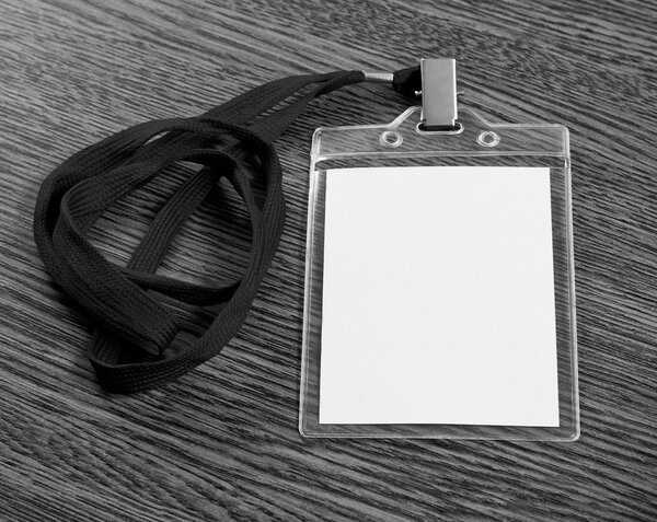 Blank badge with neckband over wooden background.