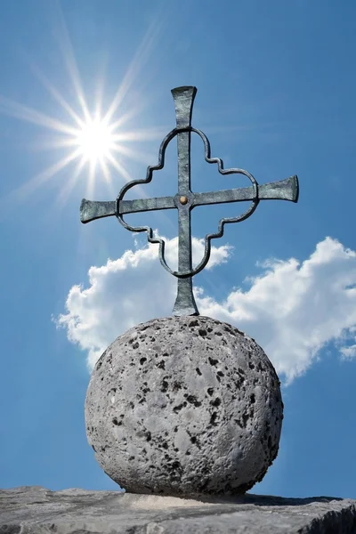 Cruz de ferro em uma bola de pedra, luz do sol brilhante — Fotografia de Stock