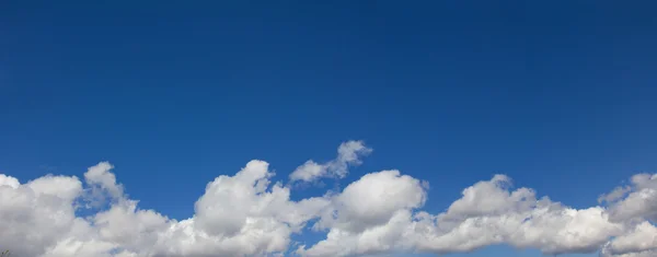 Kupovité mraky a jasné modré nebe nad — Stock fotografie