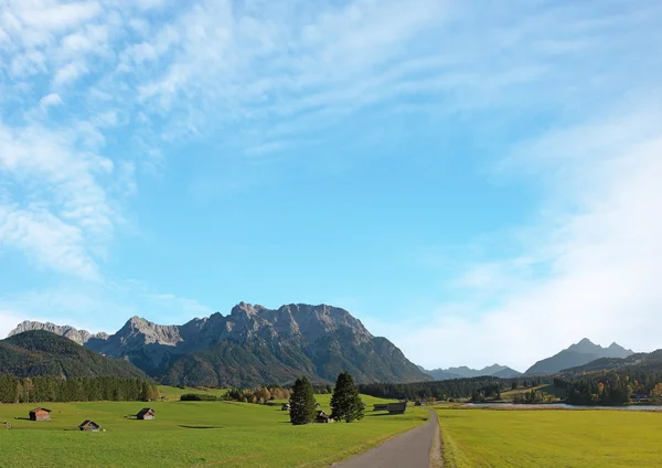 Paysage rural avec cabanes près de mittenwald, fond bleu ciel — Photo