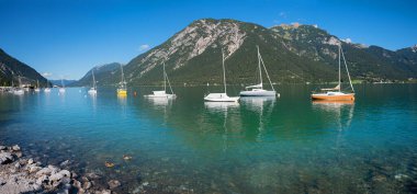 idyllic blue lake Achensee with moored sailboats, view to Rofan mountains, austria