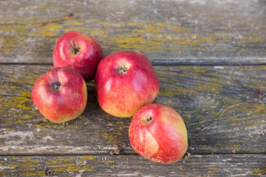 Eski püskü bir masada dört kırmızı elma.