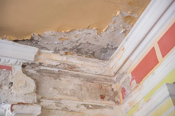 damaged edge of an abandoned room, with peeling plaster and paint, yellow ceiling