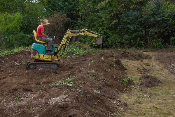Man smoothing terrain with a mini digger — Stock Photo, Image