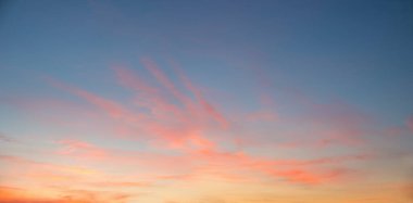 Sky panorama with orange evening glow. Delicate pink wispy clouds and blue above. sunset background.