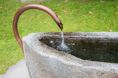 Kavisli bakır musluğu olan taş yalak. Kolları buz gibi suda sertleştirmek için diz üstü çök..