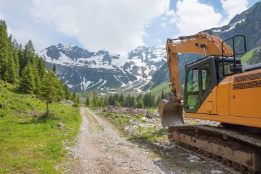 Büyük bir kazı makinesi. Kış mevsiminden sonra akarsu yatağında çalışmak için gerekli. Stillup Valley, Avusturya. Mayrhofen yakınlarındaki alp manzaralı Tyrol..