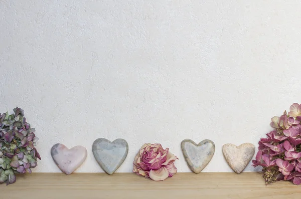 Светлый мраморный фон с сердцами и сушеными цветами — стоковое фото