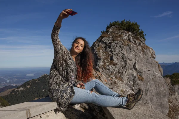 Bir duvarda oturan ve bir selfie çekim genç kadın — Stok fotoğraf