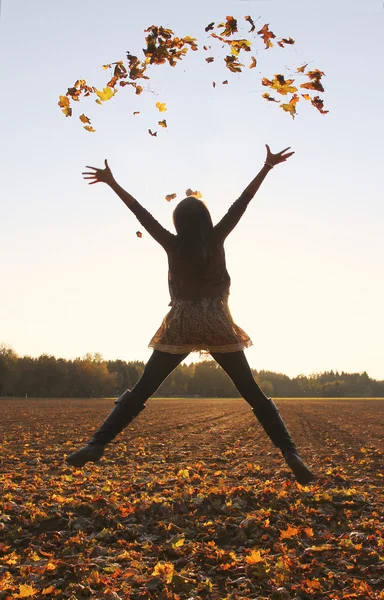 Springendes Teenager-Mädchen, das Blätter in die Luft wirft — Stockfoto