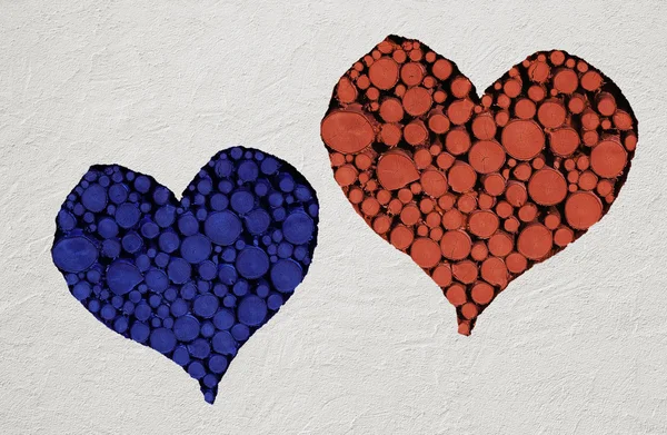 Red and blue heart, filled with logs on stone wall — Stock Photo, Image