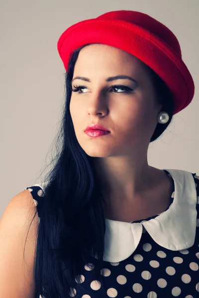 Молодая женщина с вдумчивым видом в красной шляпе — стоковое фото