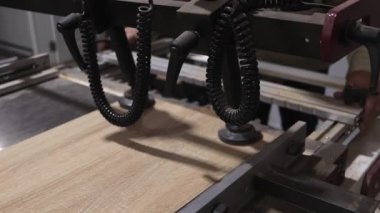 Video, bir mobilya tahtasını profesyonel bir ahşap işçiliği makinesine yerleştirme ve yerleştirme sürecini, onu hassas sondaj veya değirmen işlemleri için hazırlarken gösteriyor..