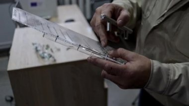 Eğitim atölyesi, öğrencilerin mobilya üretiminde profesyonel becerilerde ustalaşmalarına yardımcı olan kapı kollarındaki delikleri doğru olarak işaretlemek için bir model gösteriyor..