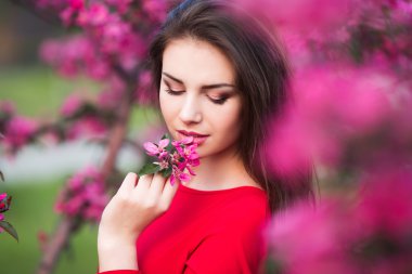 Ağaçlar ve çiçeklerle çiçeği parkta mutlu güzel ve genç birbayan.