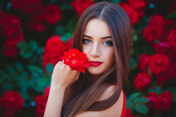 Bellissimo ritratto di sensuale bruna giovane donna vicino alle rose rosse — Foto Stock