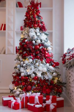 Parlak, modern oturma odasının içinde şöminesi ve Noel ağacı ve hediyelerle süslenmiş rahat bir kanepe.