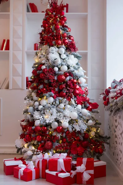 Parlak, modern oturma odasının içinde şöminesi ve Noel ağacı ve hediyelerle süslenmiş rahat bir kanepe.