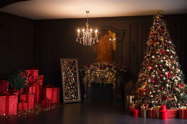 Interior of luxury dark living room with fireplace and chandelier decorated with Christmas tree and gifts — Stock Photo, Image