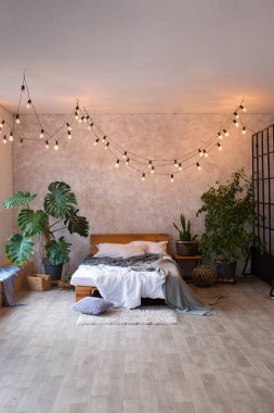 Lüks stüdyo dairesinin rahat yatak odası. Büyük panoramik penceresi ve yeşil bitkisi olan, tavan arası tarzı bedava..