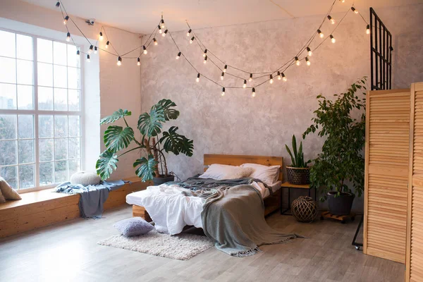 고급 스튜디오 아파트의 아늑 한 침실 지역, 큰 파노라마 창 과 녹색 식물 이 있는 다락방 스타일의 무료 배치. — 스톡 사진