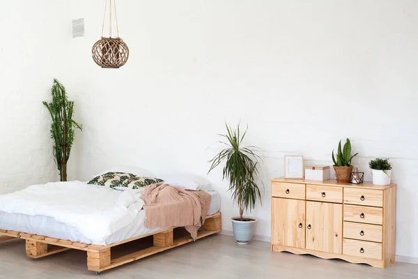 Design intérieur confortable d'un studio moderne de style scandinave. Une grande chambre spacieuse aux couleurs claires avec lit en bois et mobilier de luxe élégant et coûteux. — Photo