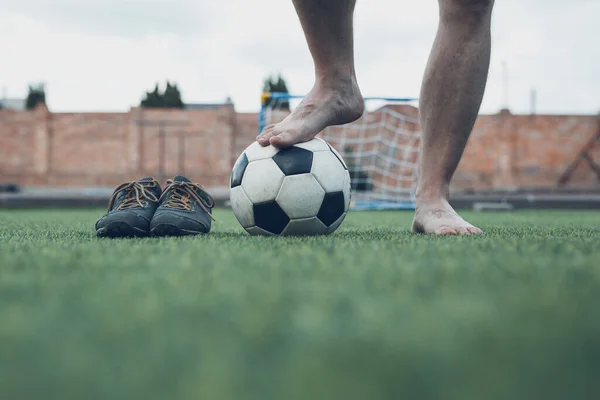Pernas de jogador de futebol descalço irreconhecível contra grama artificial. Bola de futebol, sapatos de futebol de rua. Espaço de cópia. — Fotografia de Stock