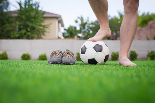 Pernas de jogador de futebol descalço irreconhecível contra grama artificial. Bola de futebol, sapatos de futebol de rua. Espaço de cópia. — Fotografia de Stock