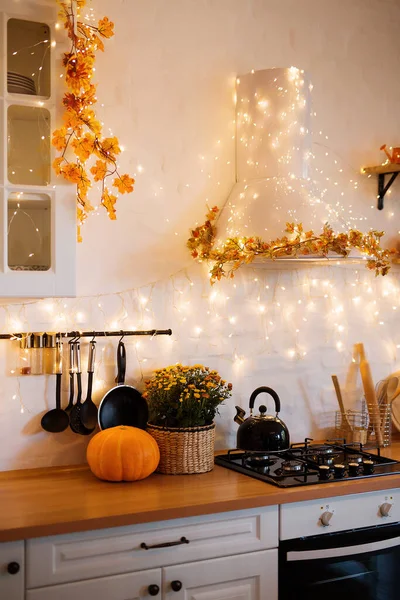 Autumn kitchen interior. Red and yellow leaves and flowers in the vase and pumpkin on light background