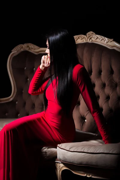 Schöne Dame im roten Kleid auf Luxus-Sofa — Stockfoto