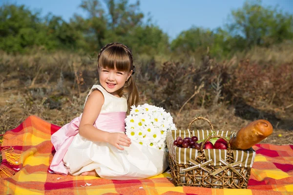 Ragazza carina con fiori che fanno picnic in estate — Foto Stock