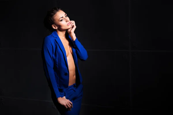 Sexy young woman with perfect body wearing blue jacket and pants. Beautiful fashion model posing in dramatic light without lingerie — Stock Photo, Image