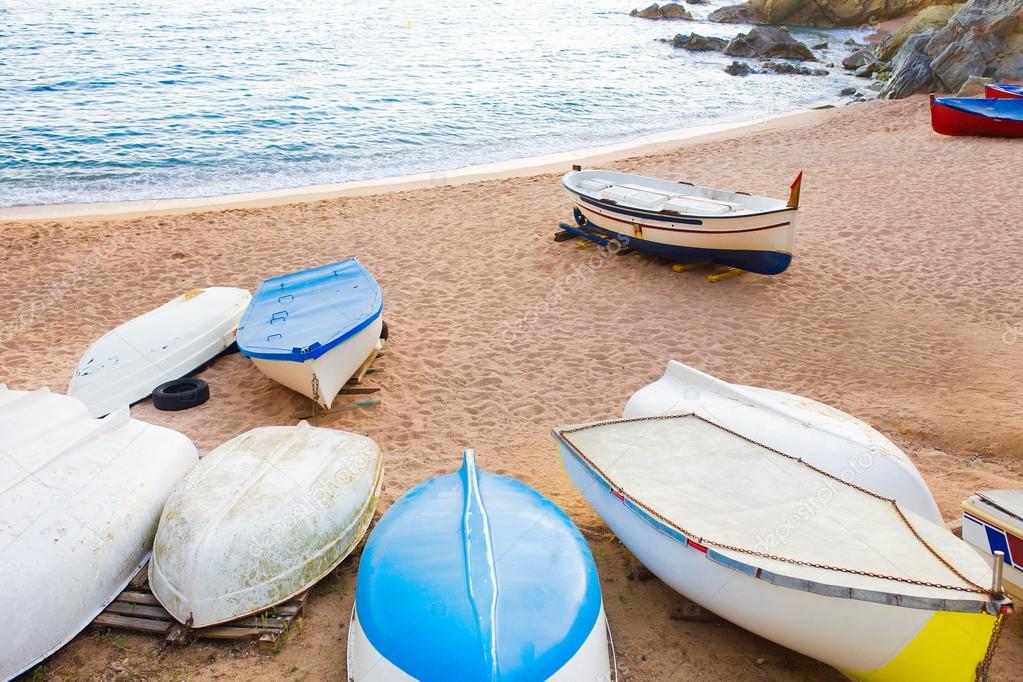 Old small boats on sandy beach. Weathered and dirty dinghies scattered across the sand