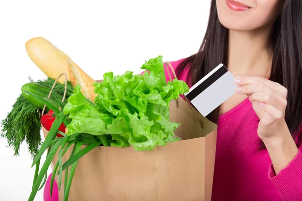 Hermosa joven con tarjeta de crédito sosteniendo comestibles en bolsa de papel ecológico. Consumo femenino en la tienda de comestibles. Aislado — Foto de Stock