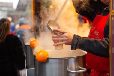 Sıcak sıcak şarap bir kış Noel pazarında şenlikli bir fincana dökülür, büyük bir tencerede narenciye ile birlikte buhar yükselir..