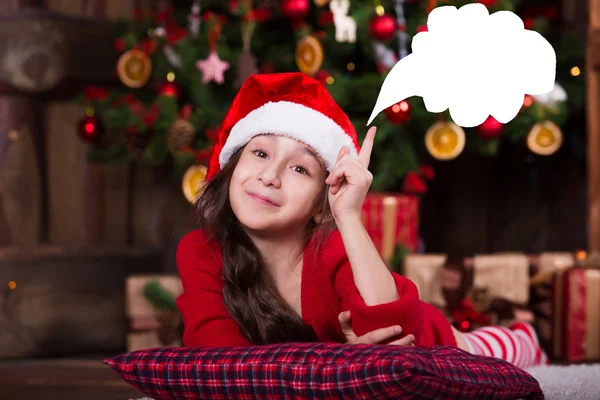 Beautiful Santa girl dreaming near the Christmas tree, making a wish. New year atmosphere — Stock fotografie