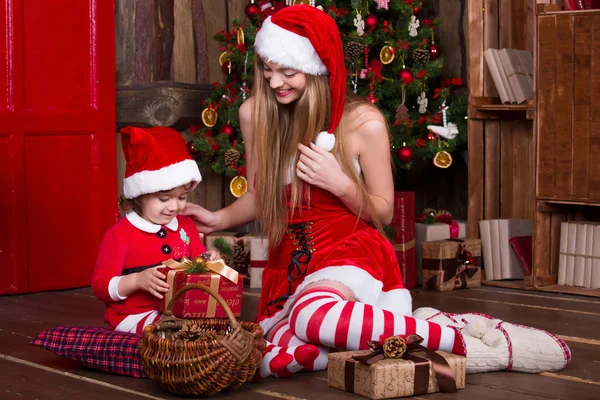 Cute girls sitting with presents near Christmas tree — Stock fotografie