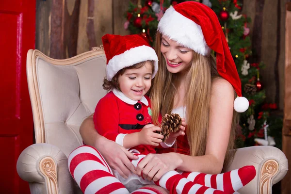 Two girls wearing xmas dress and hat decorating Christmas tree. New year interior. — Stock fotografie