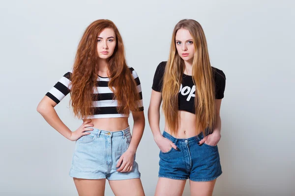 Twee mooie sexy jonge meisjes in jeans broek op witte achtergrond — Stockfoto