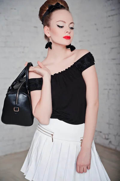 Mulher jovem sexy bonita em roupas de moda posando ao lado da parede de tijolo branco com saco preto . — Fotografia de Stock