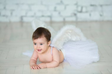 Oturma ve havuç yeme Melek kanatları giyinmiş kadar şirin bir bebek portresi.