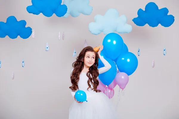 Söt liten prinsessa flicka stående bland ballonger i rummet över vit bakgrund. Titta på kameran. Barndom. — Stockfoto