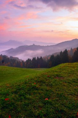 Sveti Tomaz Kilisesi, sonbaharda güneş doğarken Slovenya, Avrupa 'da Skofja Loka yakınlarında sisli bir vadide bir tepede.