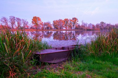 Macaristan, Avrupa 'da günbatımında ön planda eski ahşap teknelerle Tisza sahilinde güzel sonbahar renkleri