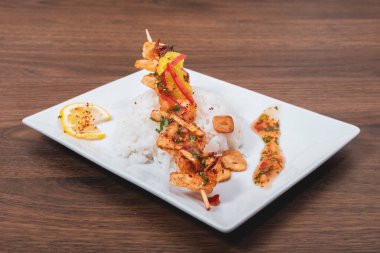 Ahşap bir arka planda servis edilen baharatlı ve pirinçli ızgara karides.