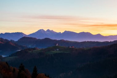 Slovenya 'nın Yukarı Carniola bölgesindeki Skofja Loka yakınlarında, sonbaharda güzel bir gündoğumunda Sveti Tomaz Kilisesi (Saint Thomas) bir tepenin üzerinde